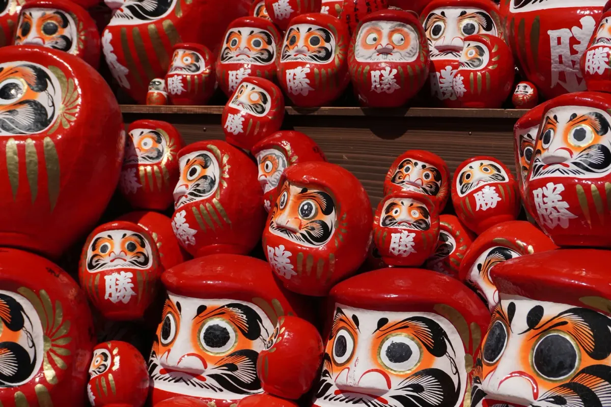 Shelves crowded with red daruma dolls, each marked with the character for victory, at Katsuo-ji temple in Minoh, Japan.